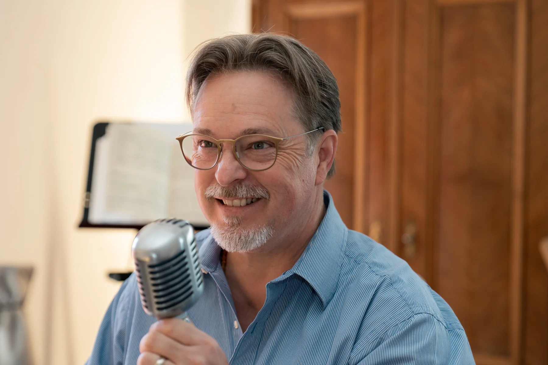 Brent lächelt und hält ein Retro-Mikrofon